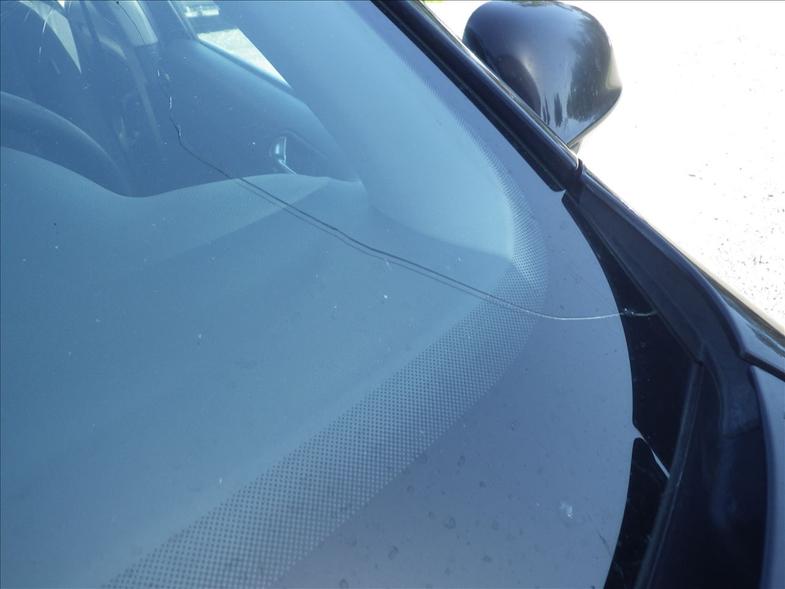 Auton tuulilasi, jossa on pitkitt&auml;inen halkeama keskell&auml;, odottamassa korjausta tai vaihtoa.