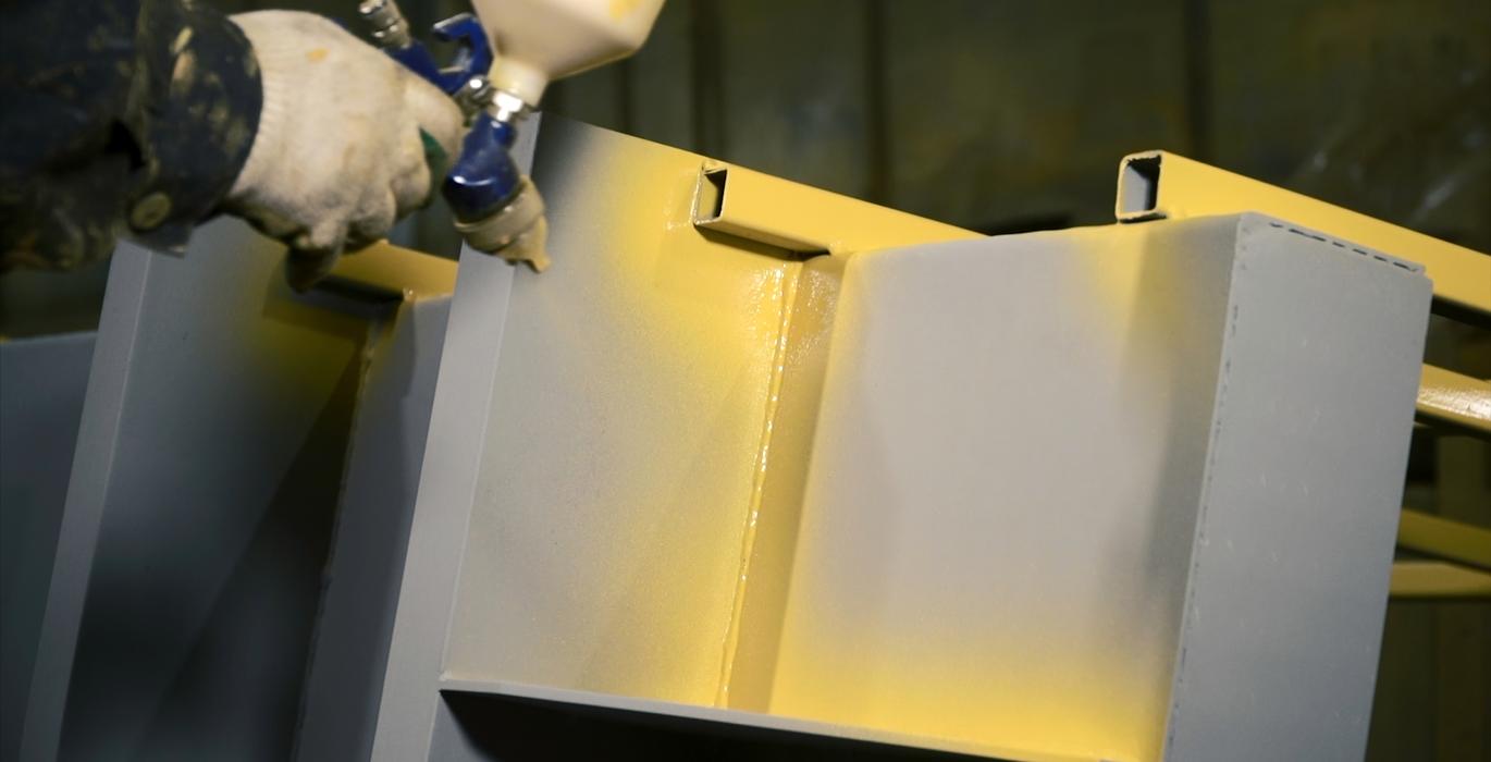 Työkoneen osan maalaus keltaisella värillä ruiskumaalausmenetelmällä.