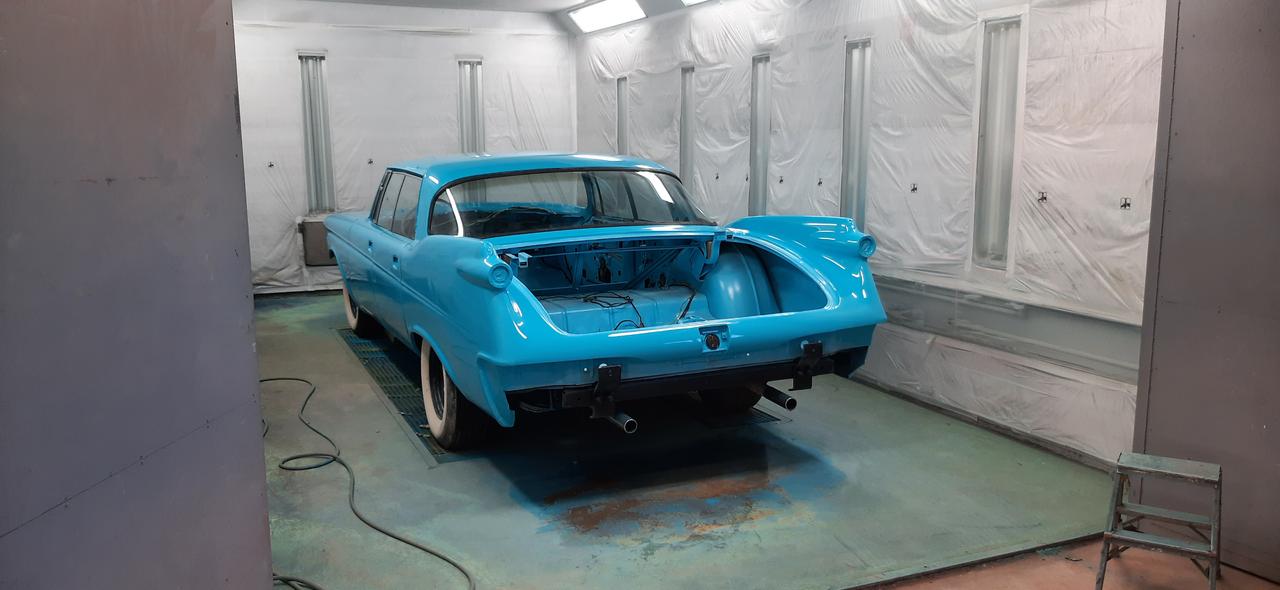 Turkoosiksi maalattu vanha auto maalauskammiossa, viimeistelyvaiheessa ilman puskuria ja valoja.